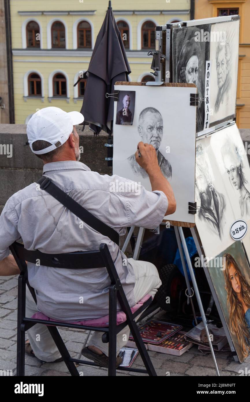 PRAGUE - CZECH REPUBLIC, AUGUST 13, 2019 : portrait painter drawing a face from a picture in a street Stock Photo