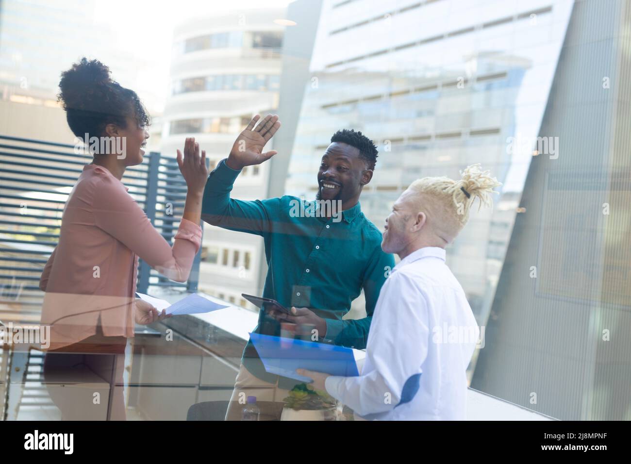 African american albino mid adult businessman looking at african american colleagues doing high-five Stock Photo