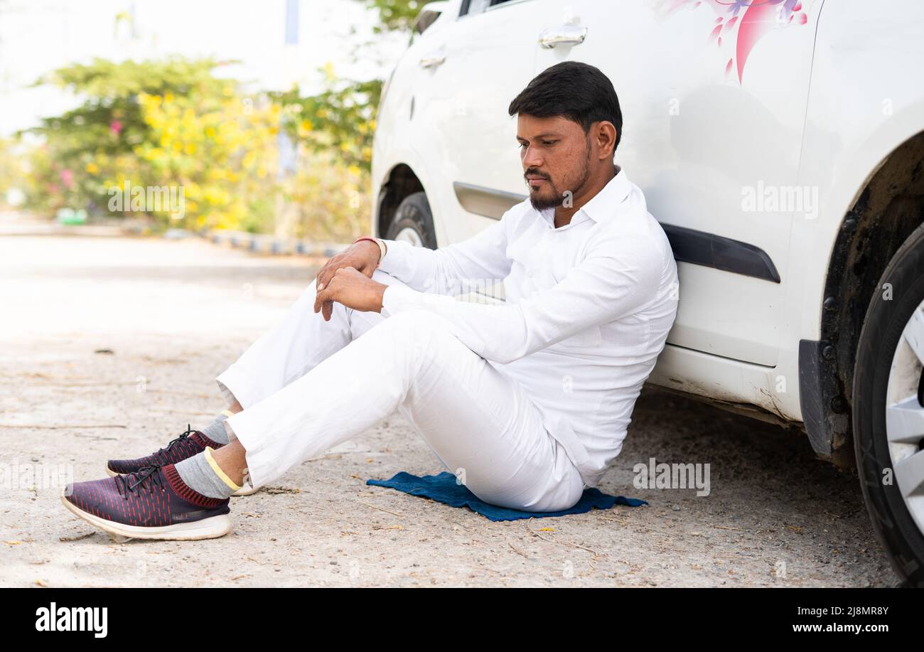 Sad thoughtful cab driver sitting by leanings to car on road - concept of business loss, bankrupt and family problems Stock Photo