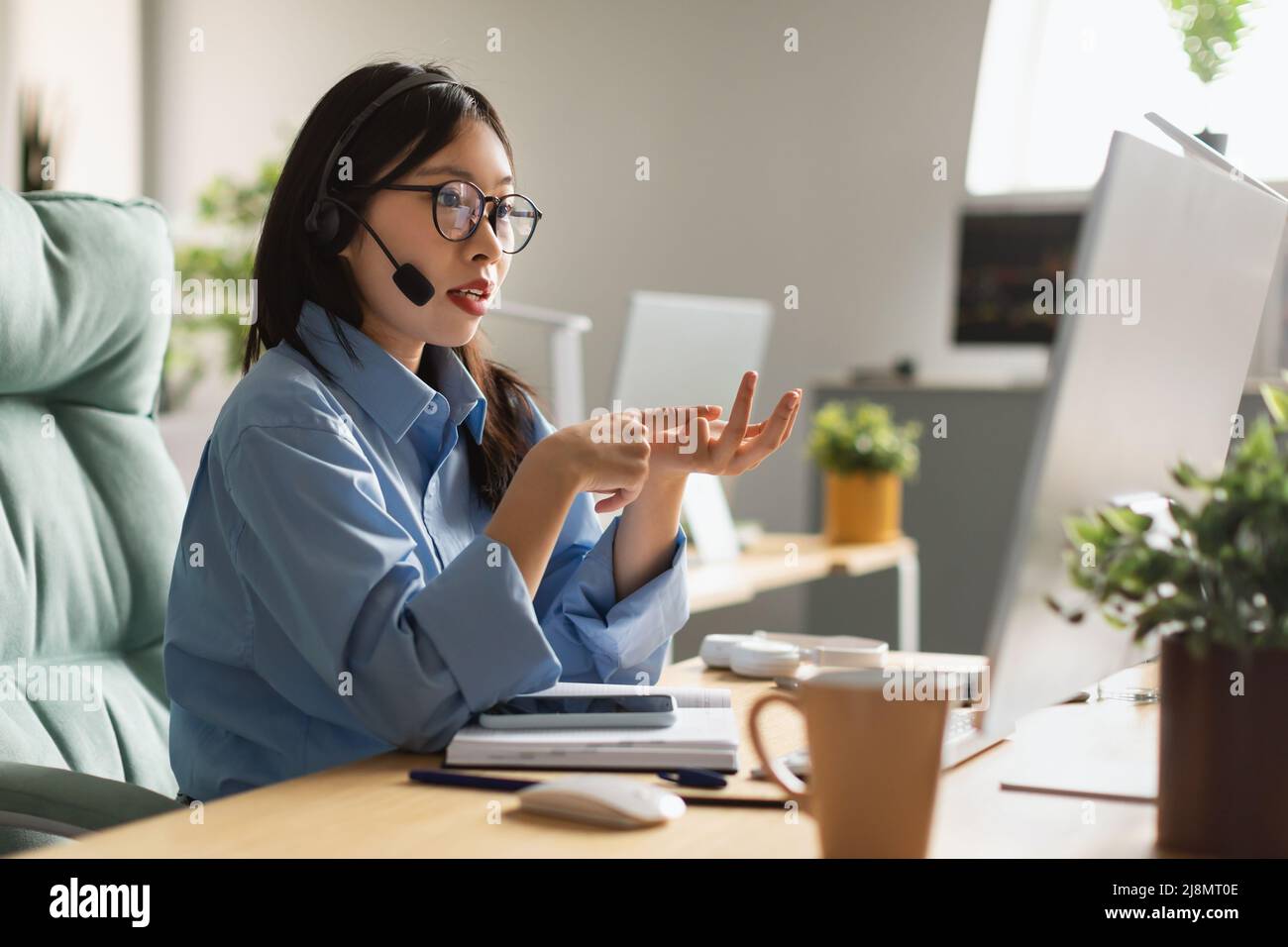 Asian woman using laptop wearing headset making video call Stock Photo ...