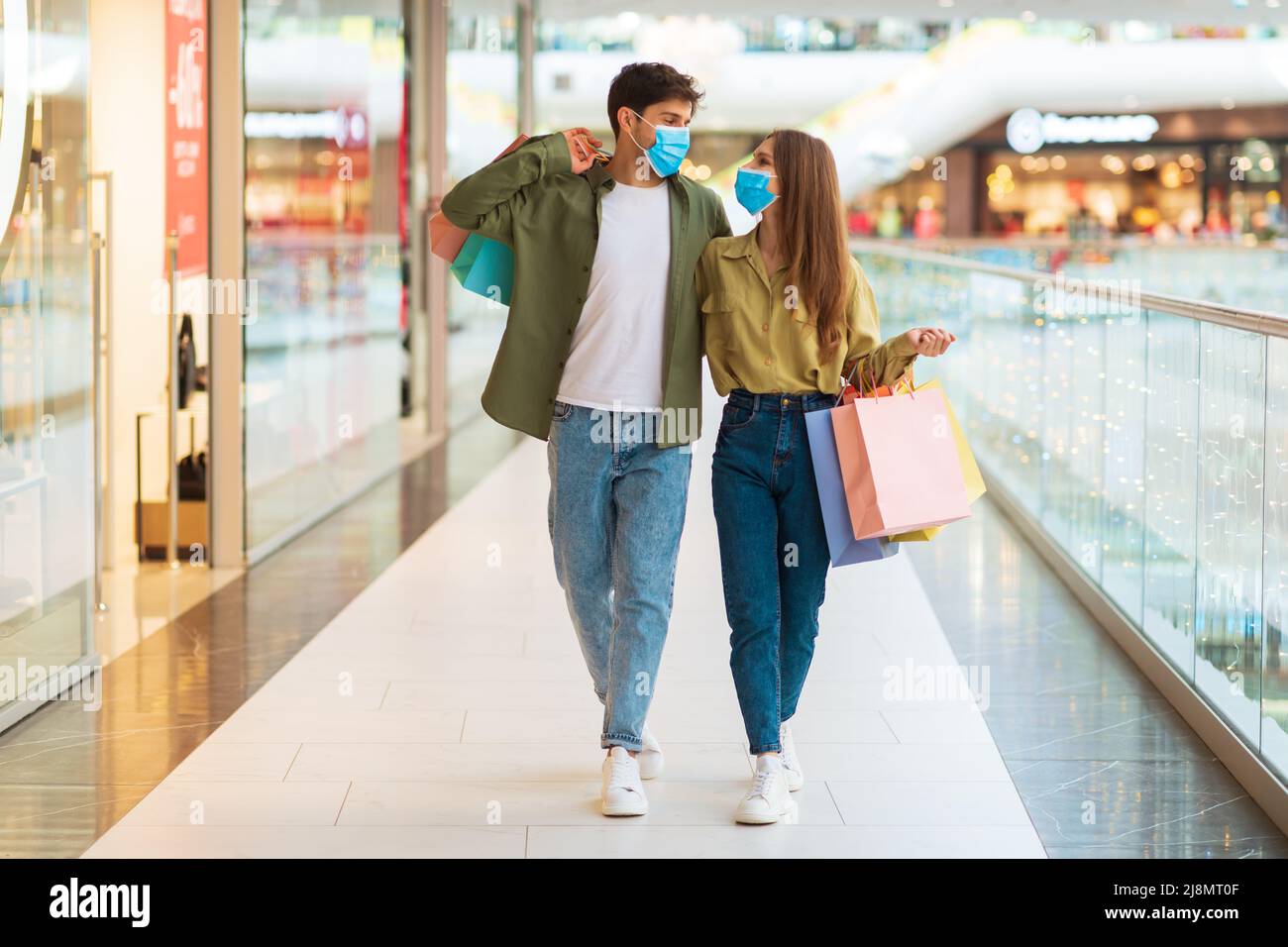 Couple Shopping Wearing Masks Walking Holding Shopper Bags In Mall