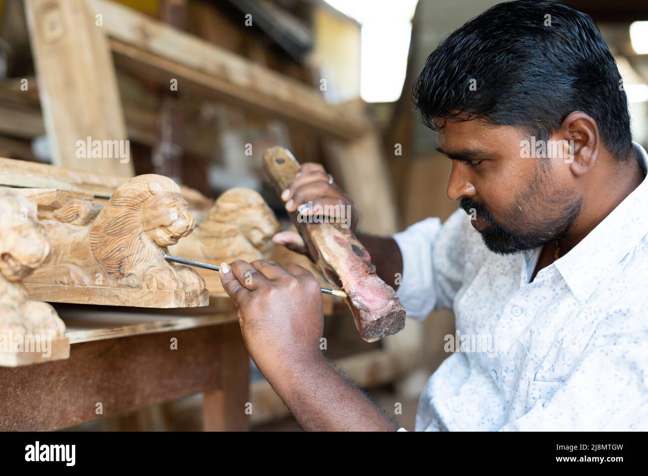 carpenter busy making wood design by shaping using carpentry tools at shop - concept of creativity, skilled labour and wood worker Stock Photo