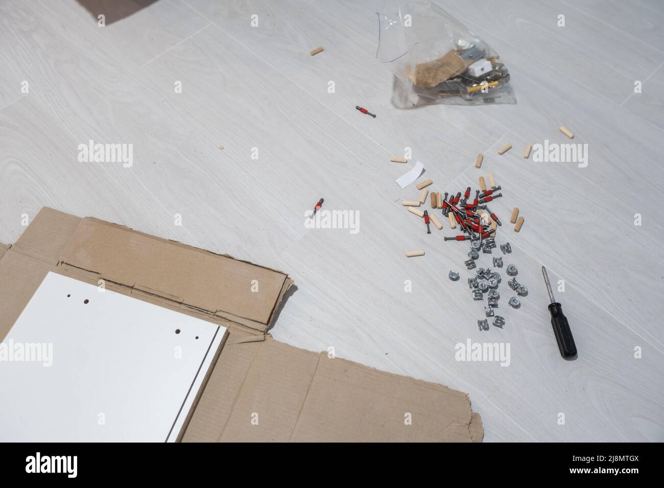 Parts of unfinished furniture, metal screws and tools lying on the ...