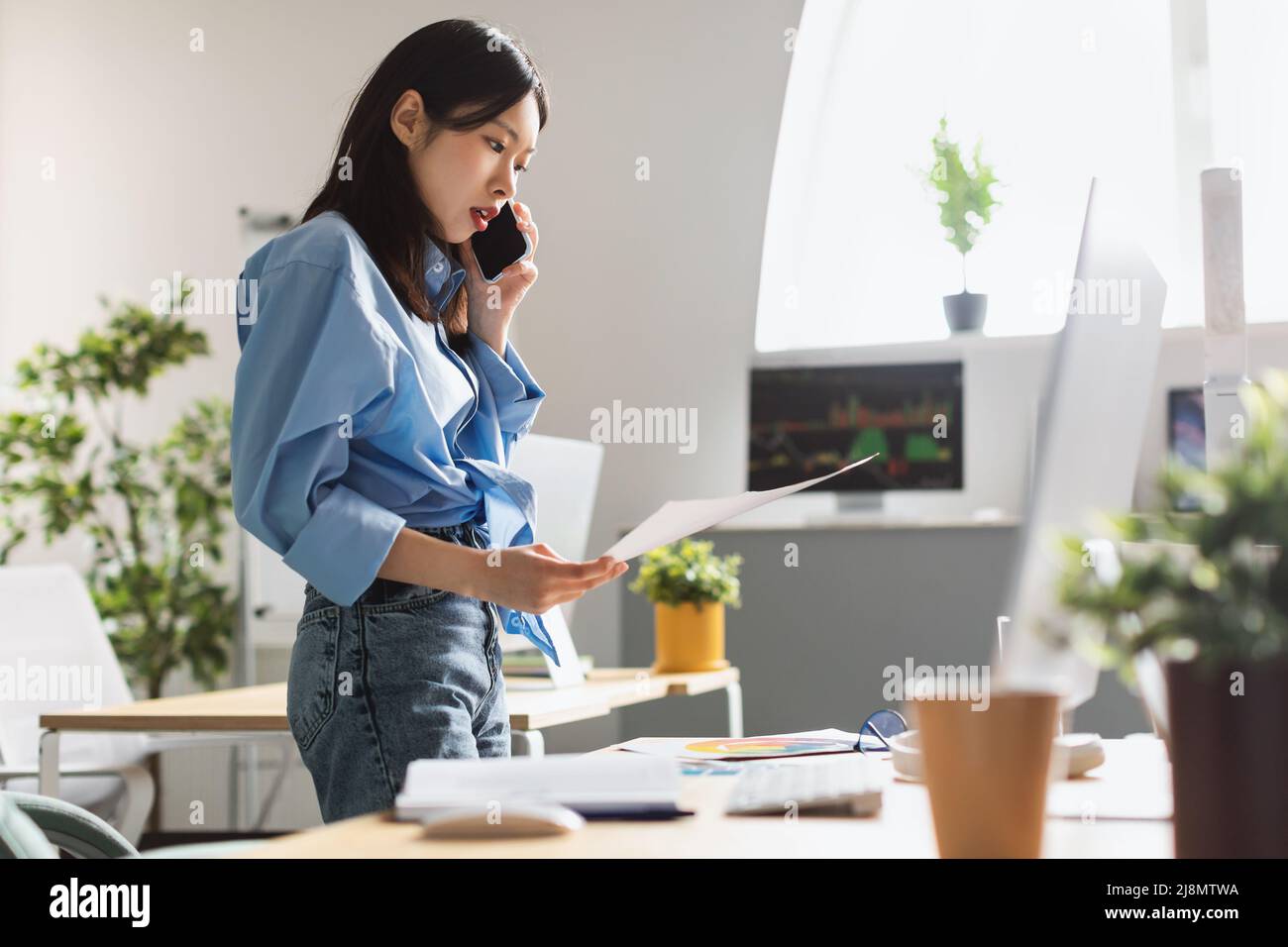 Lady holding paper reading report talking on phone at office Stock Photo