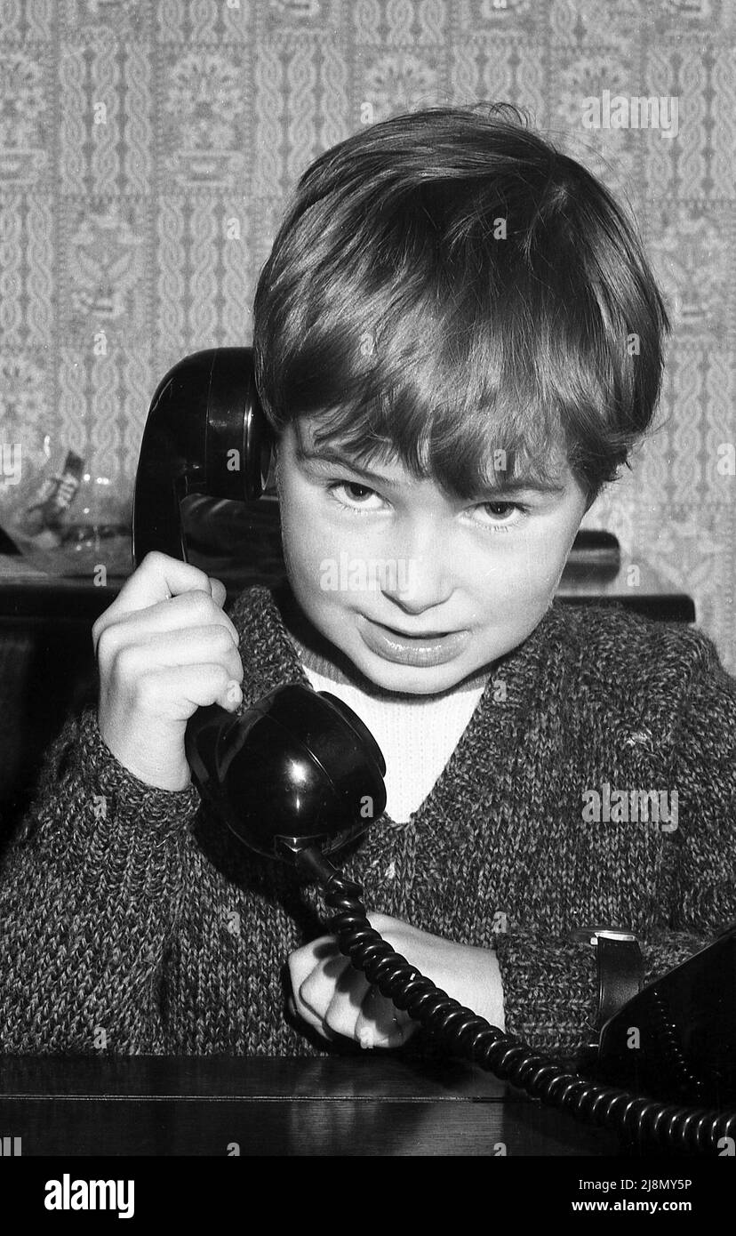 1970s, historical, a little boy holding the handset of a telephone of the era, with the receiver to his ear, England, UK. Stock Photo