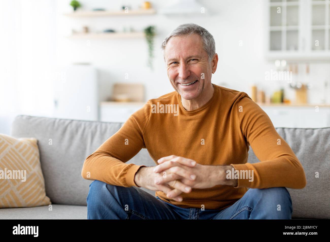 Smiling mature man sitting on the couch and posing Stock Photo - Alamy
