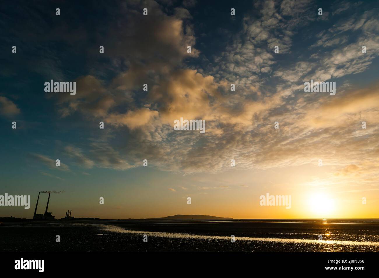 Sunrise at low tide with golden light and thin cirrus clouds. Poolbeg