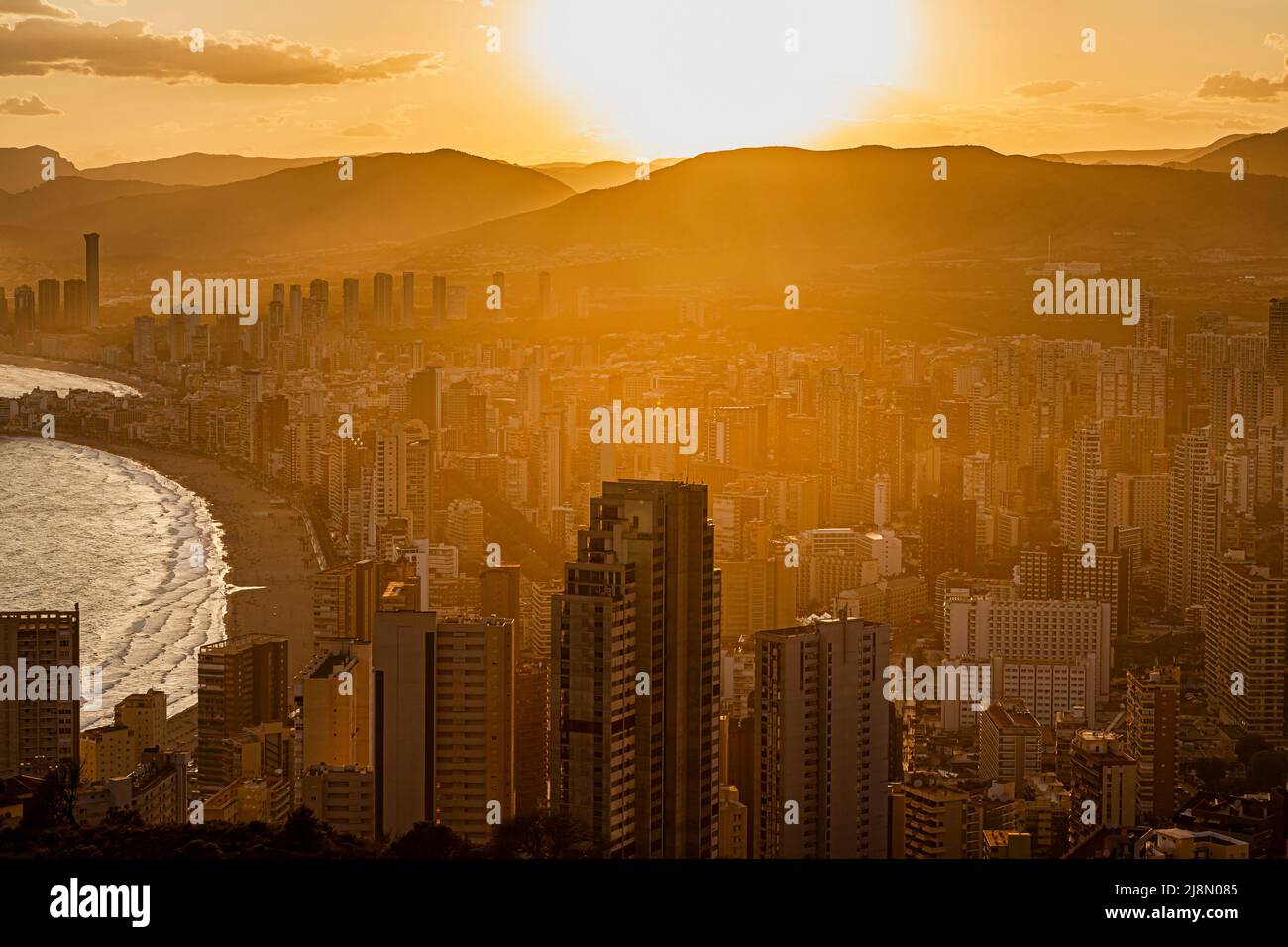 Summer sunset, with golden light through the dusty haze of high-rese apartments and hotels in Benidorm, Spain Stock Photo