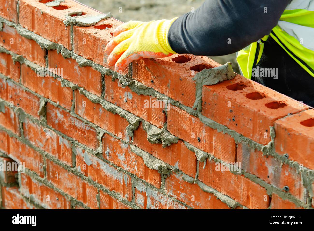 Bricklayer laying bricks on mortar on new residential house