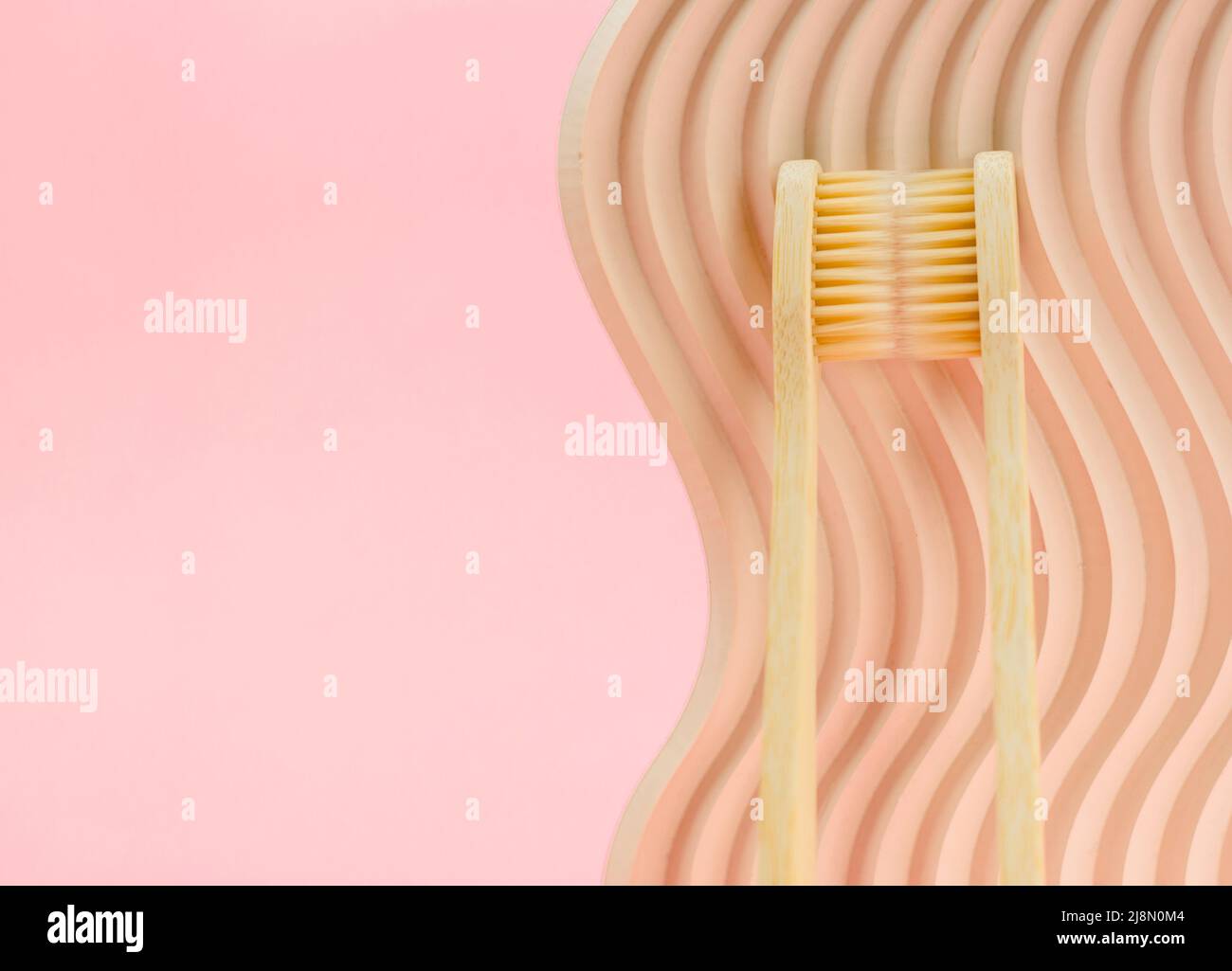 Two bamboo toothbrushes on a pink background with place for text. Eco ...