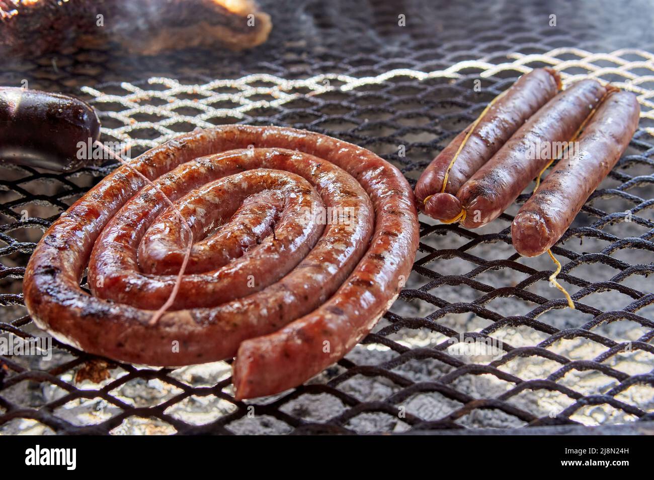 Close up of coil of a barbecue sausage and pork sausage on fire on grill. Typical argentine food on weekends Stock Photo