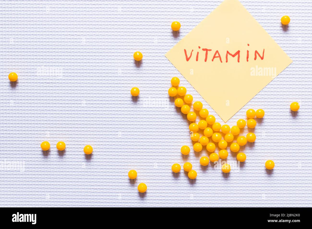 Vitamin Lettering top view of yellow round shape medication near paper note with vitamin ...