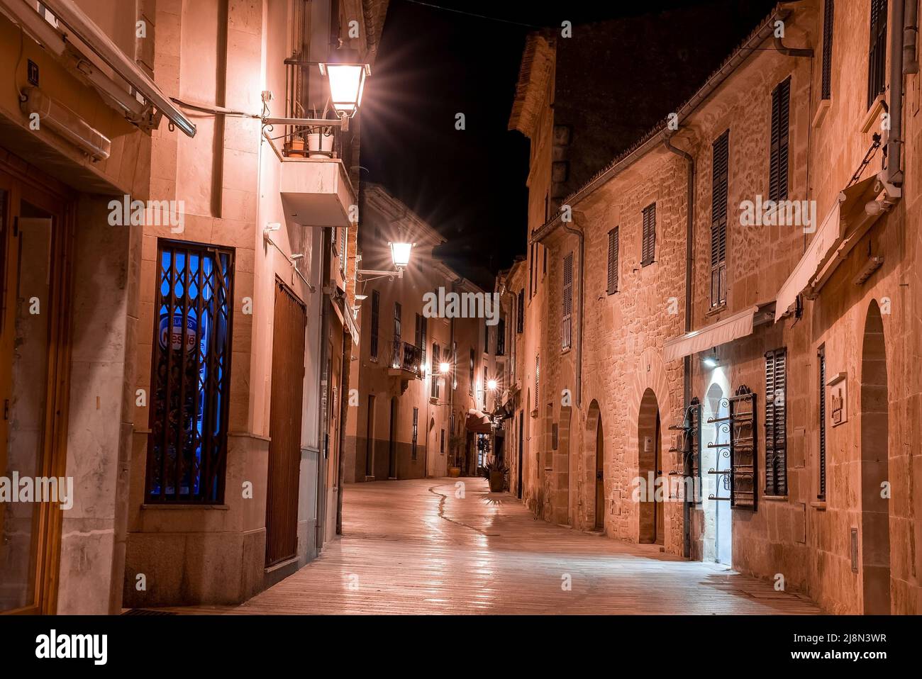 Illuminated empty alley amidst buildings in old residential town at night Stock Photo