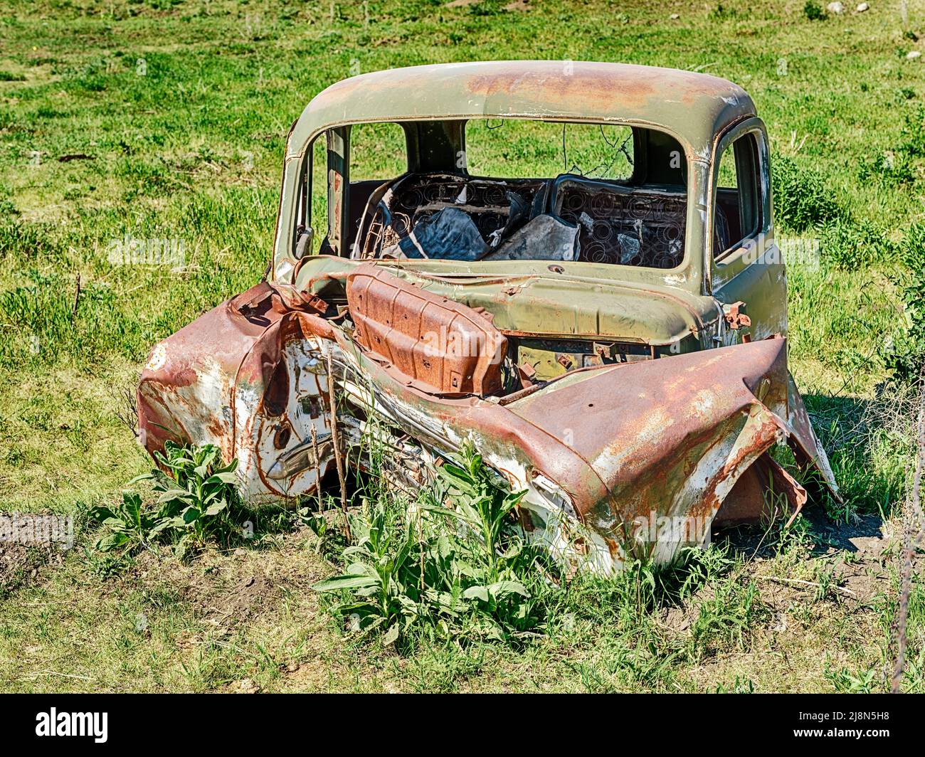 Rusting remains of a smashed up old car rest in a pasture near Molson, Washington. Stock Photo