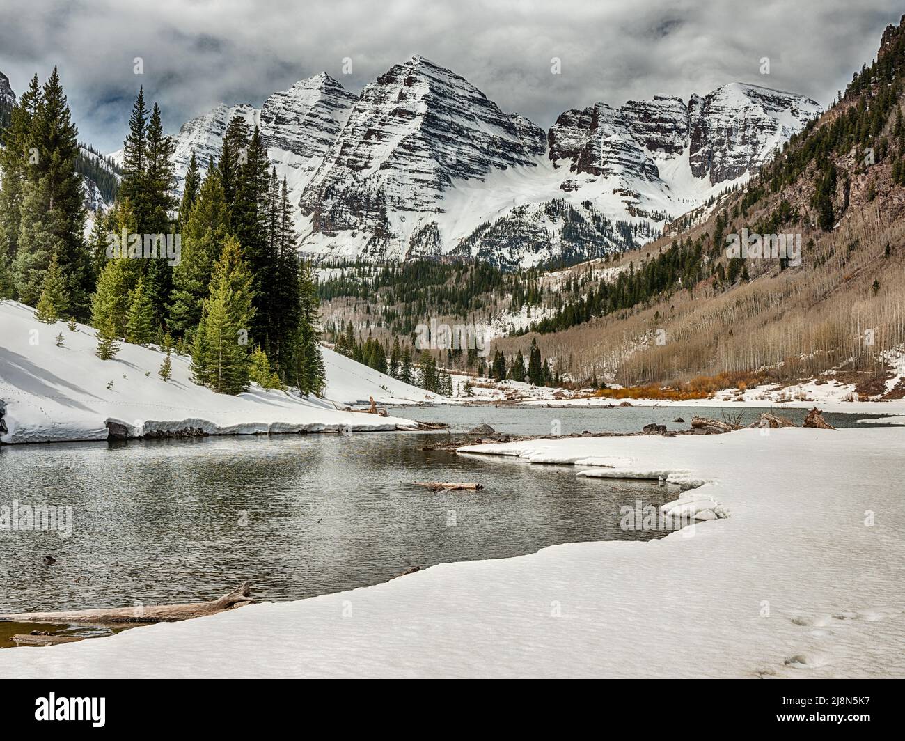 An alpine like in spring fills with runoff from the snow with the peaks of the Maroon Bells in the background. Stock Photo