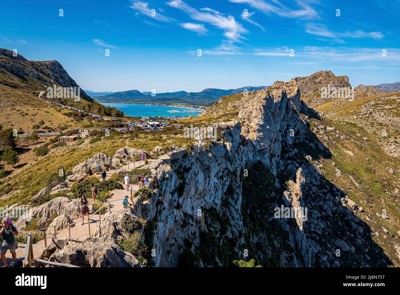 Tourists sightseeing at Mirador Es Colomer cliffs against blue sky ...