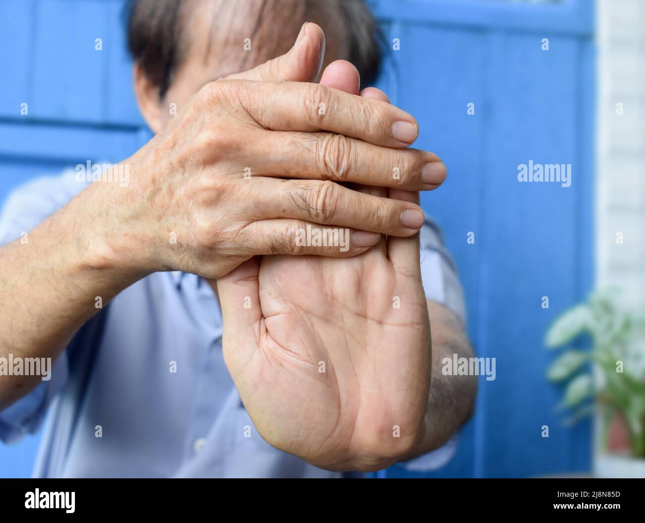 Strengthening exercise for arm muscles of Asian elder male patient with muscle spasm. Stock Photo