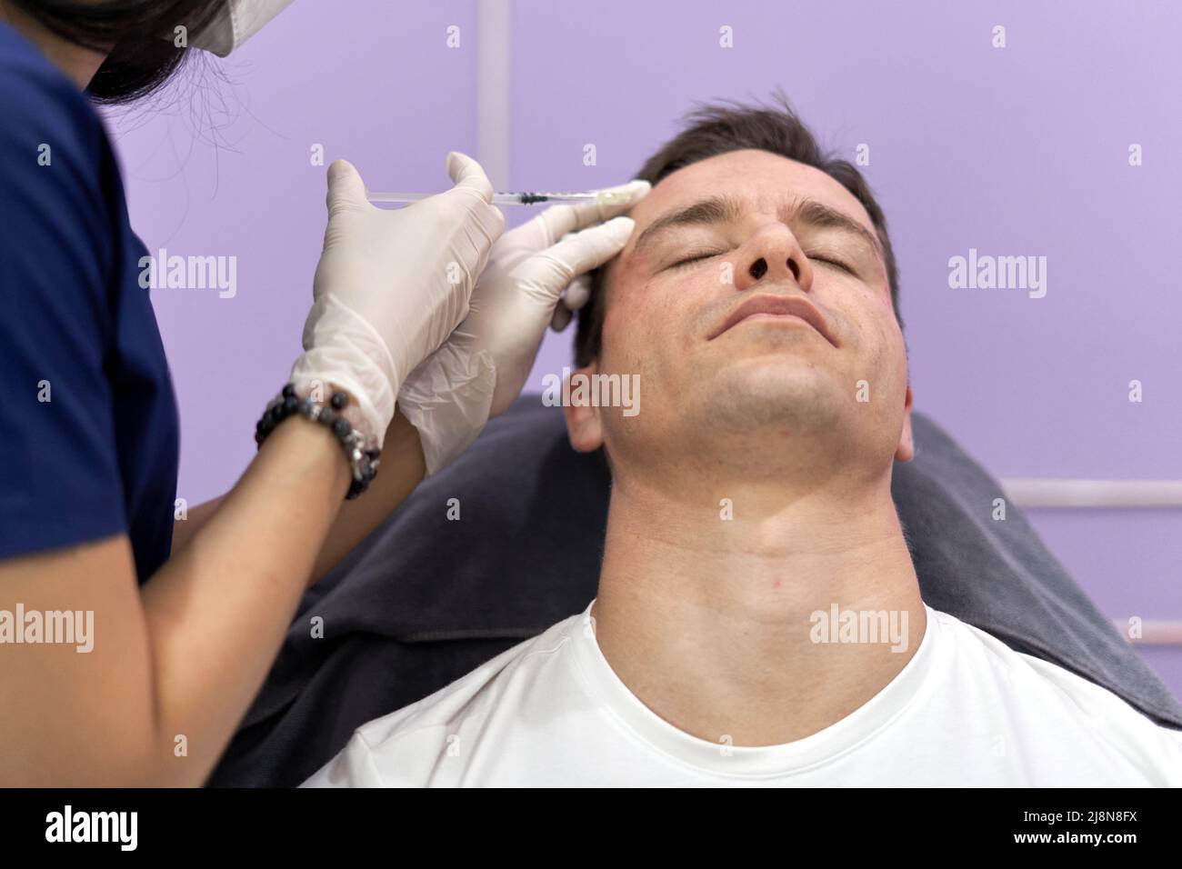 Relaxed patient getting a botox injection for facial rejuvenation treatment Stock Photo
