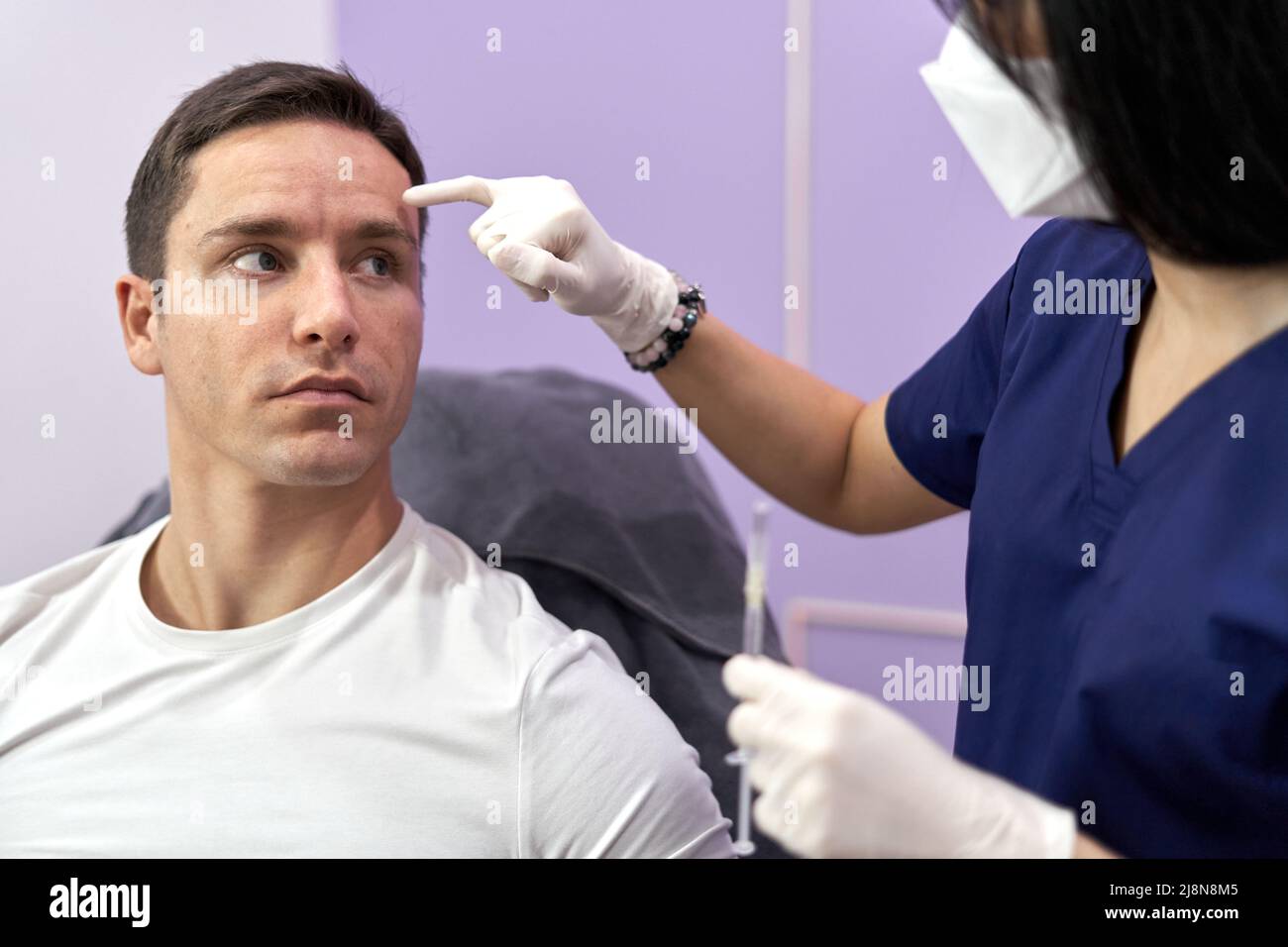 Doctor pointing to the spot she will inject a botox injection into a patient Stock Photo