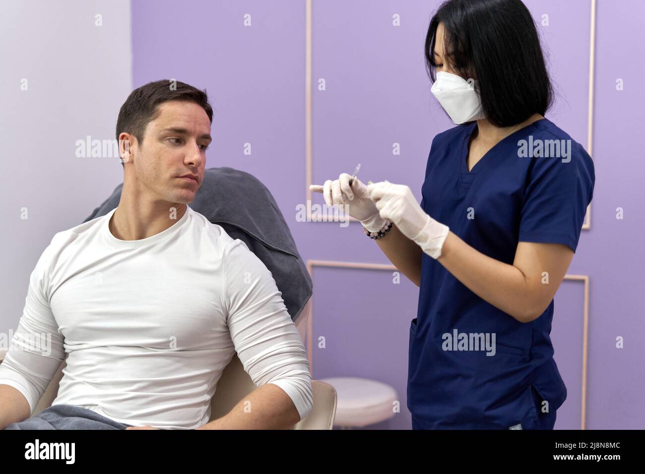 Patient watching as a doctor prepares a Botox injection for application Stock Photo