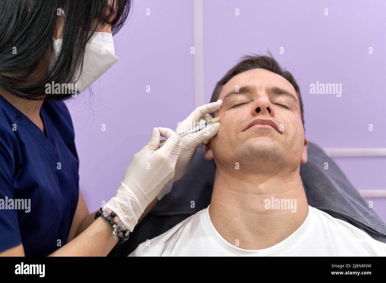 Man receiving forehead botox injection for facial rejuvenation treatment Stock Photo