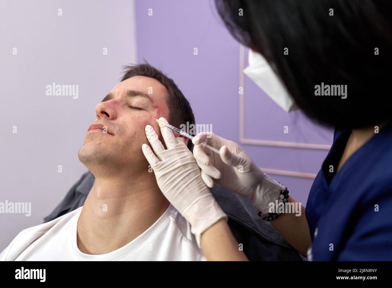 Patient closing eyes while getting a rejuvenation treatment with botox injection Stock Photo
