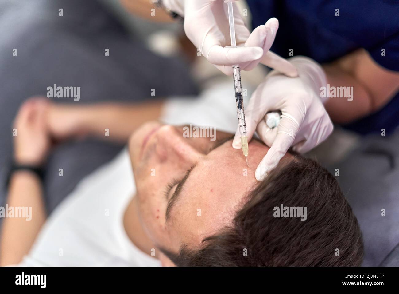 Man receiving a vaccine with collagen to perform a facial beauty treatment Stock Photo