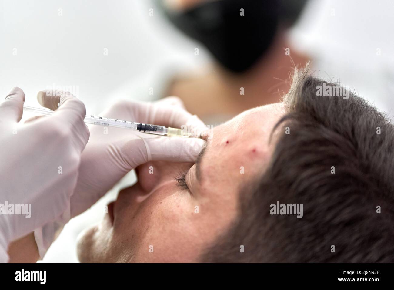 Focus on a botox injection entering the skin of a patient's forehead Stock Photo