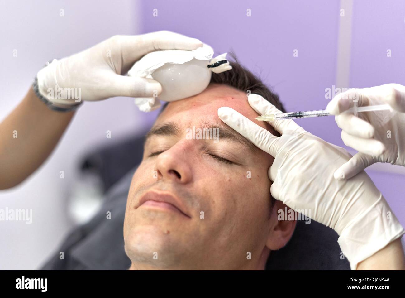 Nurse applying ice to the face of a patient while receiving a botox vaccine Stock Photo