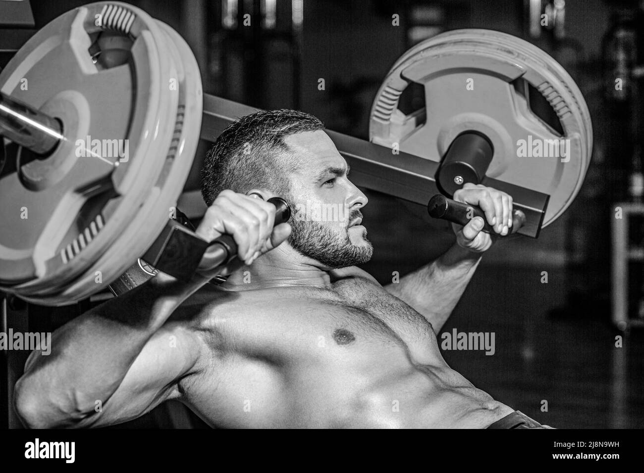 Muscular man workout with barbell at gym. Bodybuilder athletic man with six pack, perfect abs, shoulders, biceps, triceps, chest. Barbells workout Stock Photo