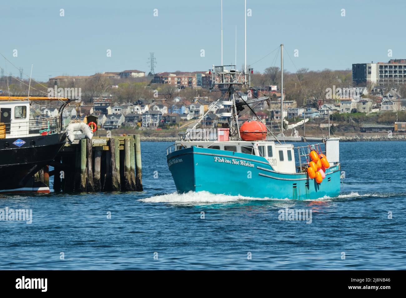 fishing boat passing by docks in Halifax harbour Stock Photo