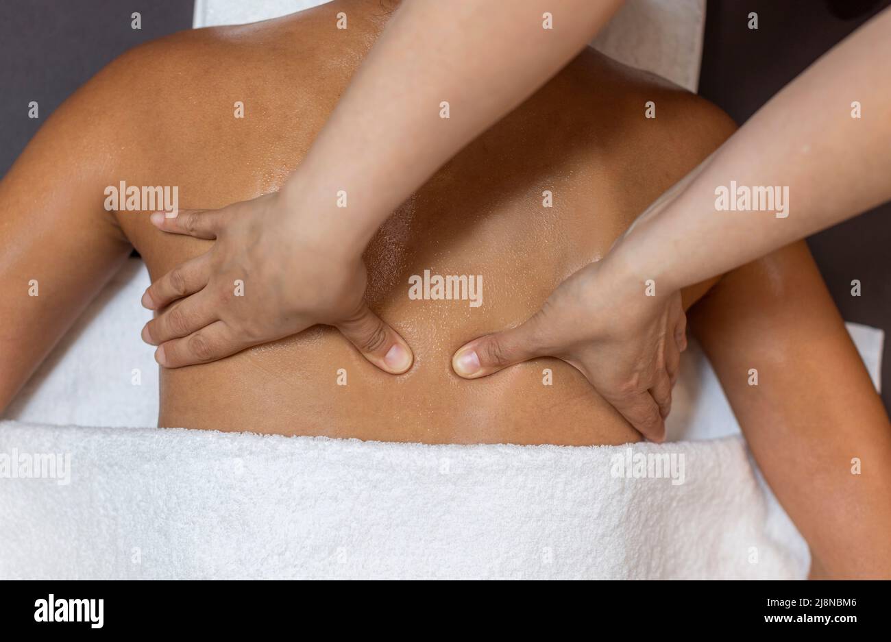 Massage therapist massaging the back of her client. Stock Photo