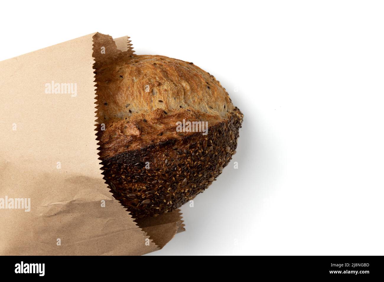 loaf of golden wheat bread with empty space for text isolated on white background, homemade baking, fresh whole grain bread close up in paper bag, top Stock Photo