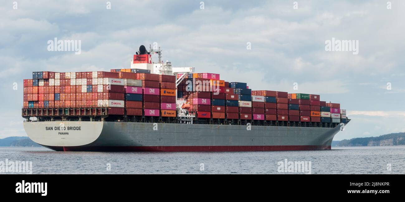 A water-level view of the huge, loaded container ship San Diego Bridge, anchored in BC's Gulf Islands while awaiting access to the Port of Vancouver. Stock Photo