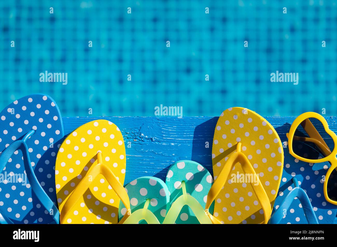 Beach flip-flops and sunglasses on blue wood against water background ...