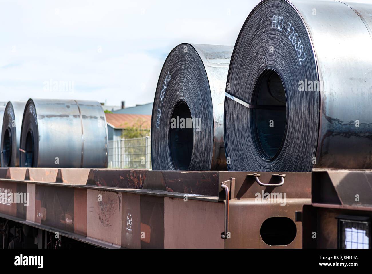 Large rolls of sheet metal lying on a freight wagon pulled by locomotives. Stock Photo