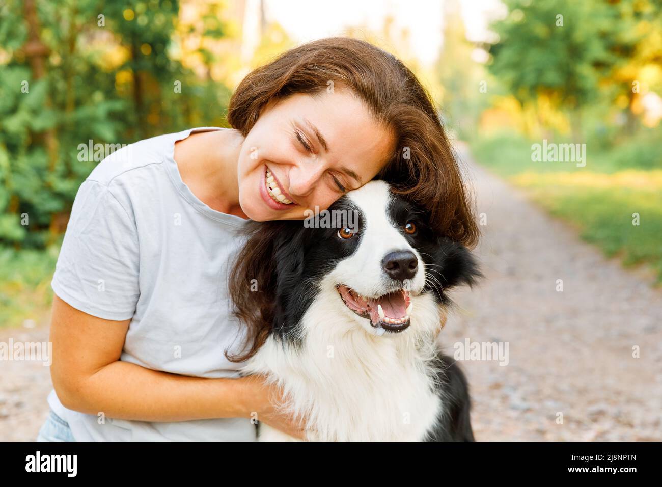 Smiling young attractive woman playing with cute puppy dog border