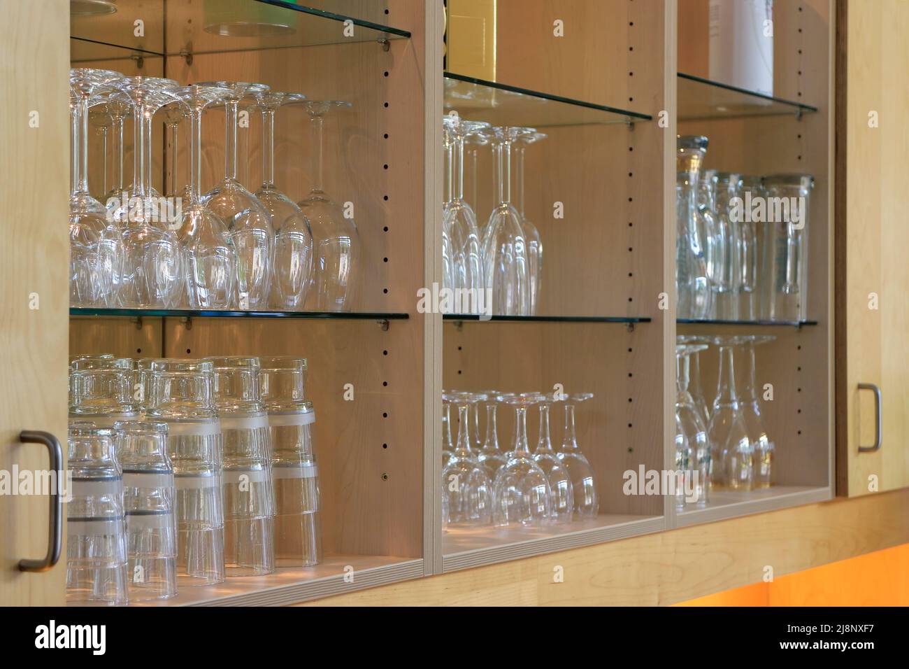 Many shiny glasses in rows on shelves inside a bar Stock Photo