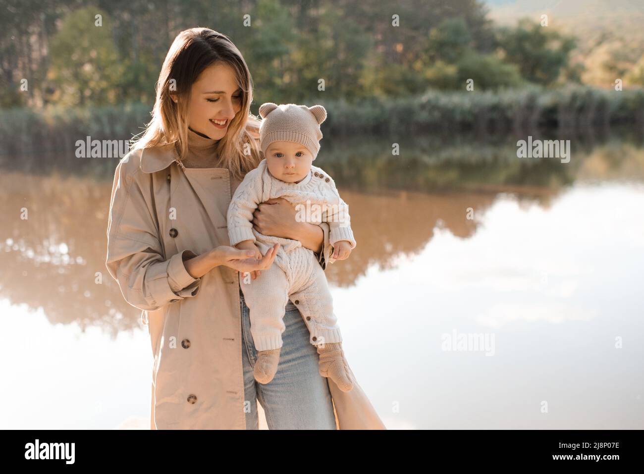 Smiling young mother playing with baby boy 1 year old wear casual clothes posing over nature