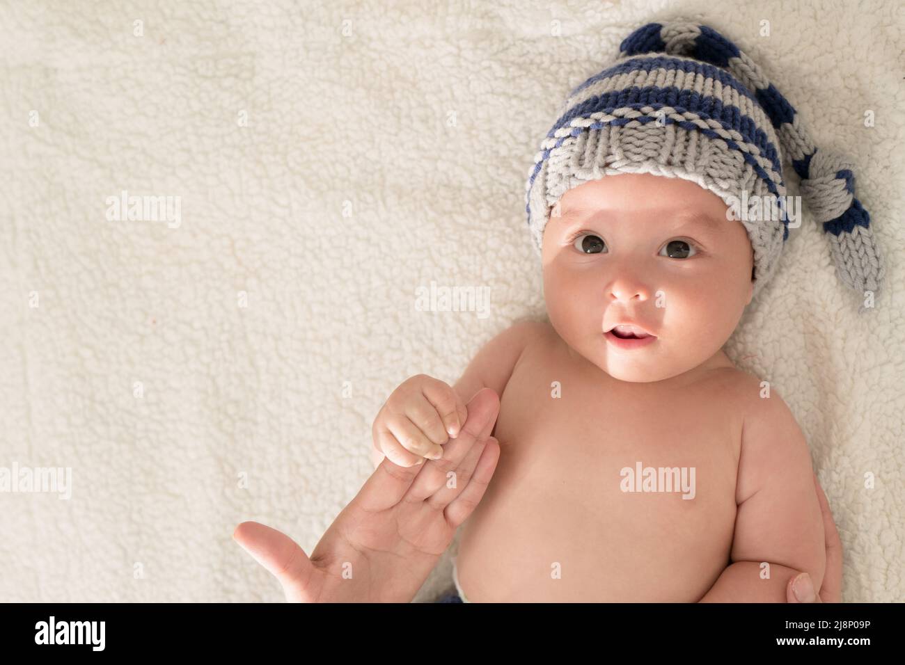 Latin babywith a surprised face at bed with a hat Stock Photo
