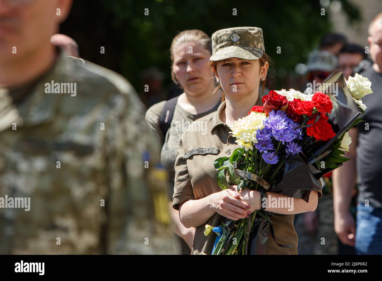 Non Exclusive: UZHHOROD, UKRAINE - MAY 16, 2022 - A servicewoman holds flowers during the farewell ceremony for Ukrainian defenders Oleksandr Serousov Stock Photo