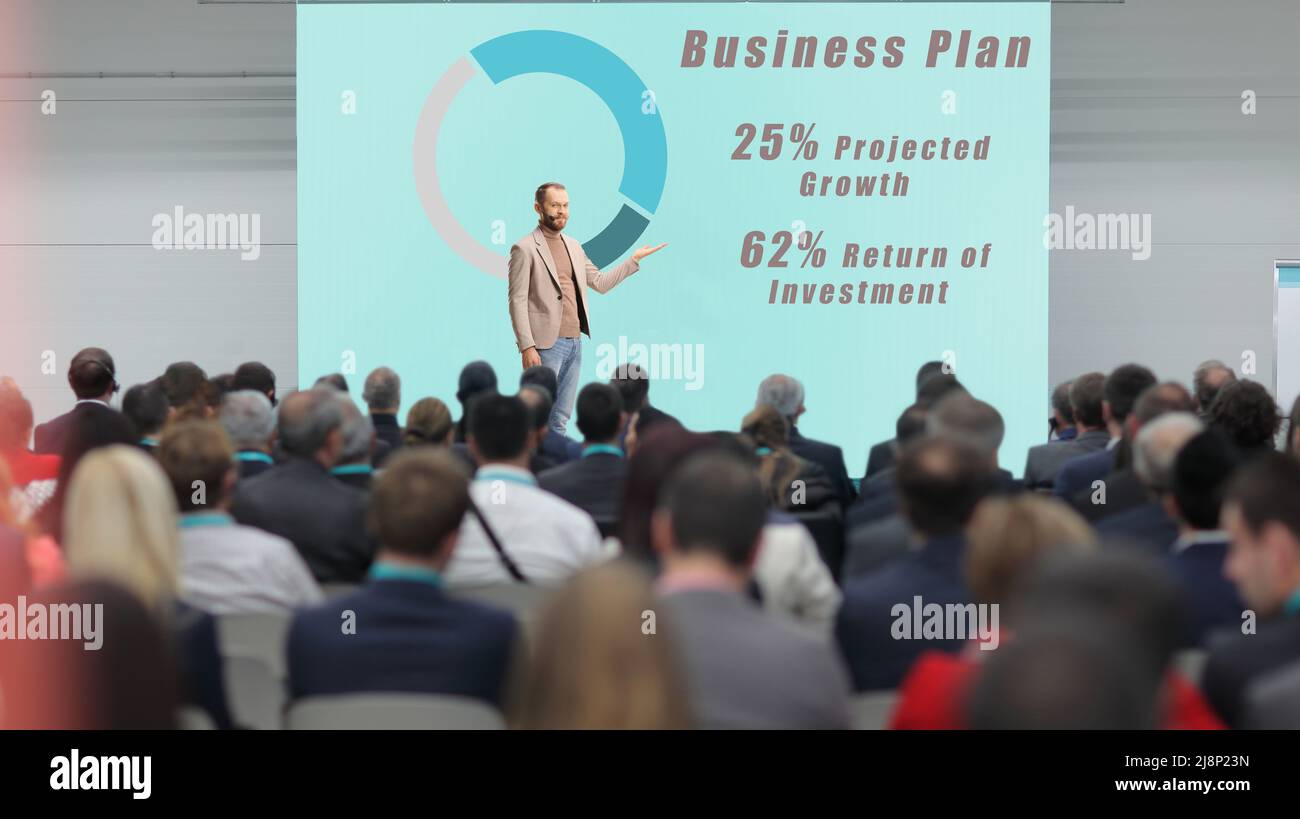 Man presenting a business plan at a conference and people listening in the audience Stock Photo
