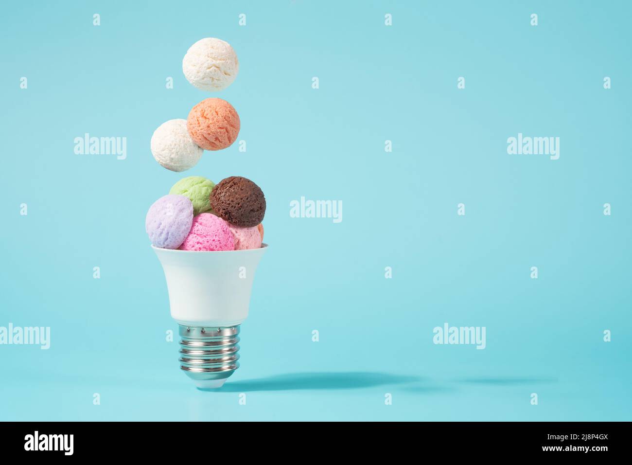Ice cream balls falling into the light bulb cone. Electricity shortage minimal concept. Stock Photo