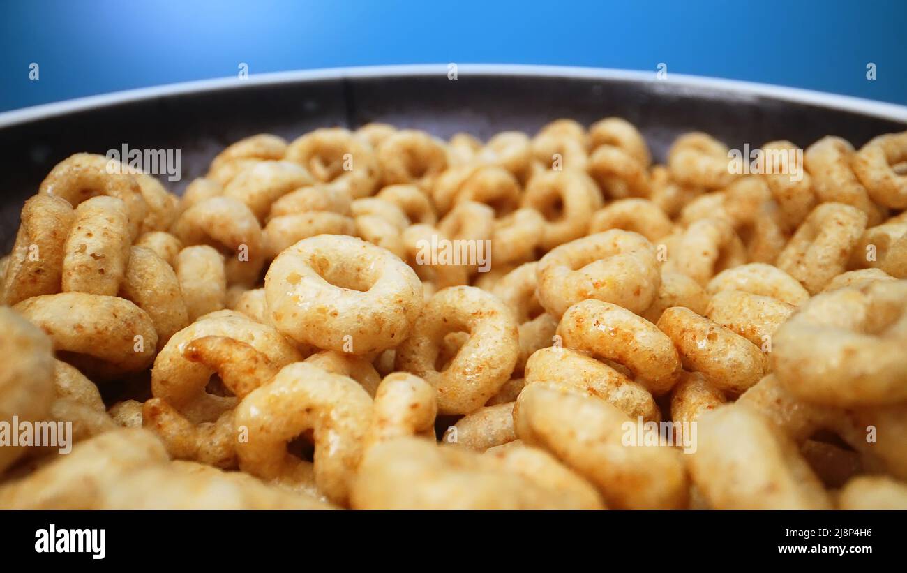 Bowl with cereal circles on blue background. Stock Photo