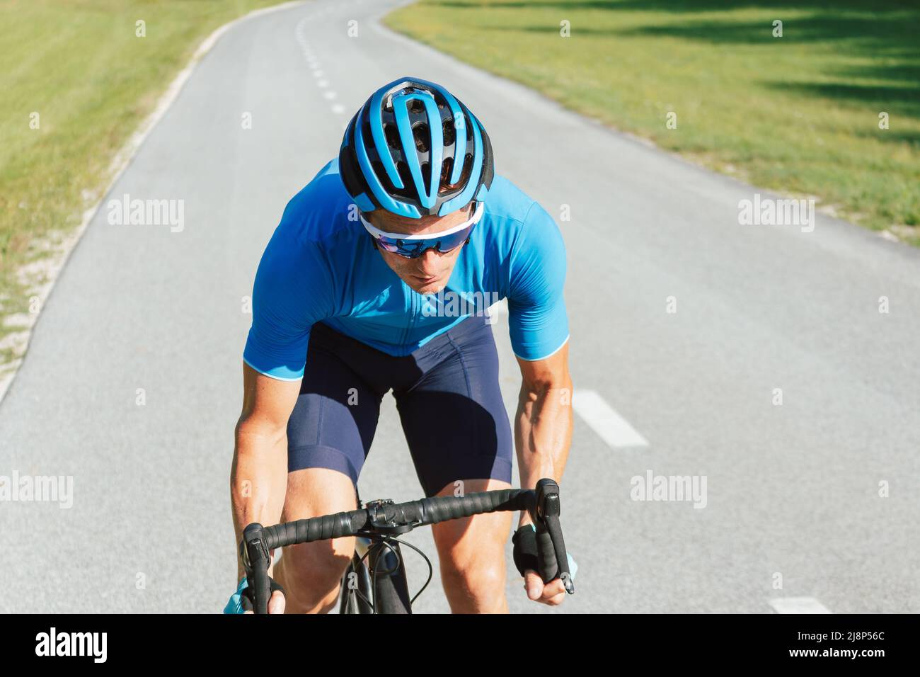 Muscular man, professional racing bicyclist sprint cycling, with posterior raised out of the saddle and pedaling hard Stock Photo
