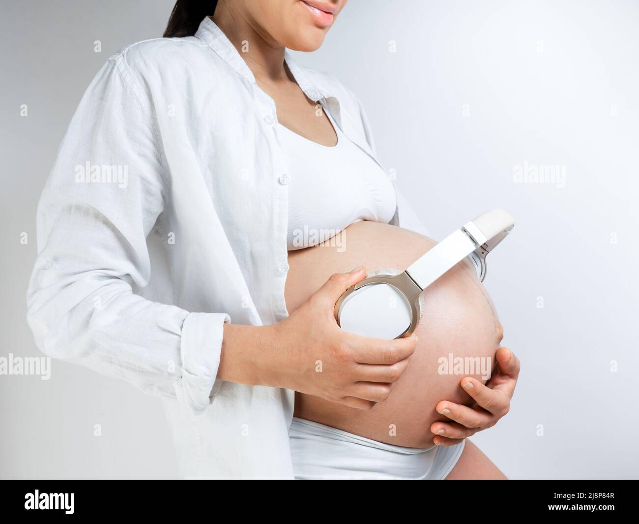 Pregnant woman music lover put the headphones on her belly to let Rebecca  enjoy the music she likes. Girl waiting for a baby keeps headphones on her  Stock Photo - Alamy