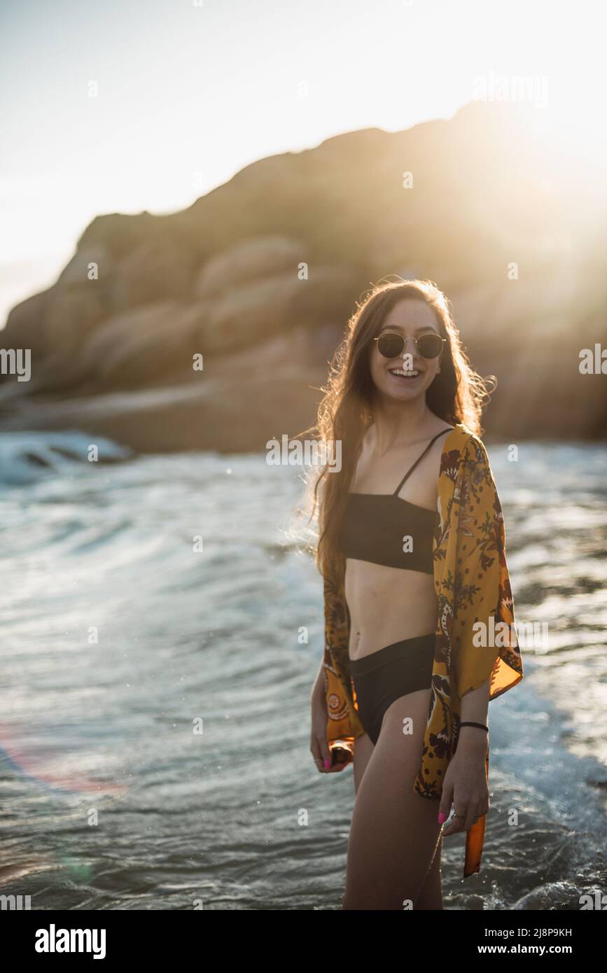 Young woman smiling with sunrise on his back on the beach Stock Photo