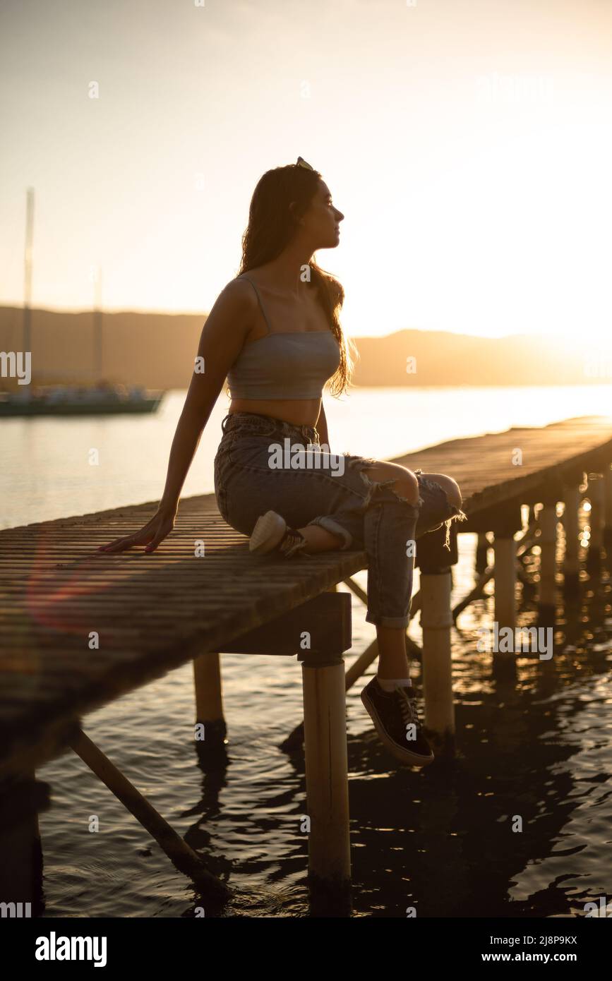 young woman sit in a lake and looking at the horizon on the sunset Stock Photo