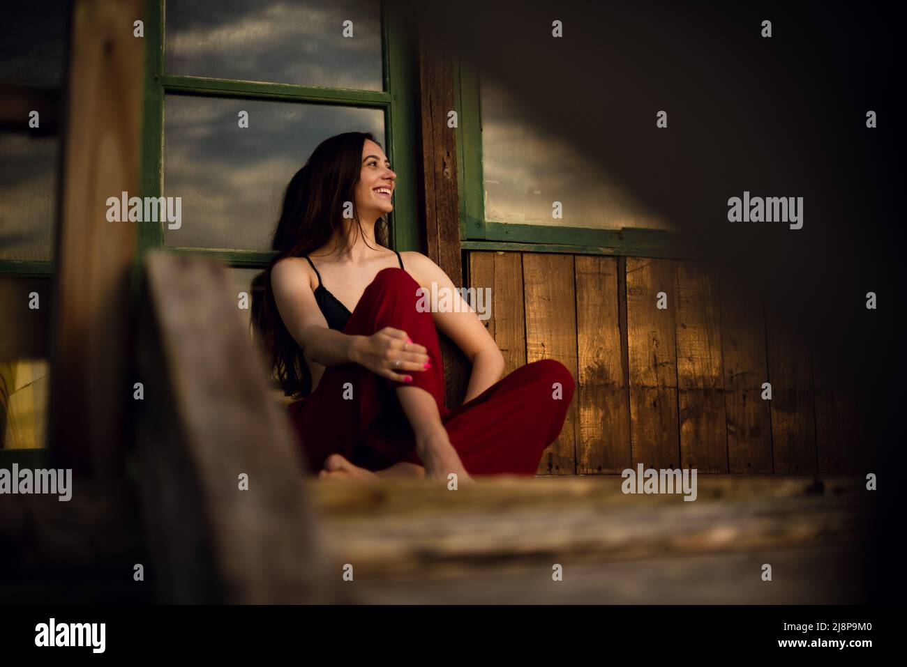 Young woman sit in front of a rise and smiling Stock Photo