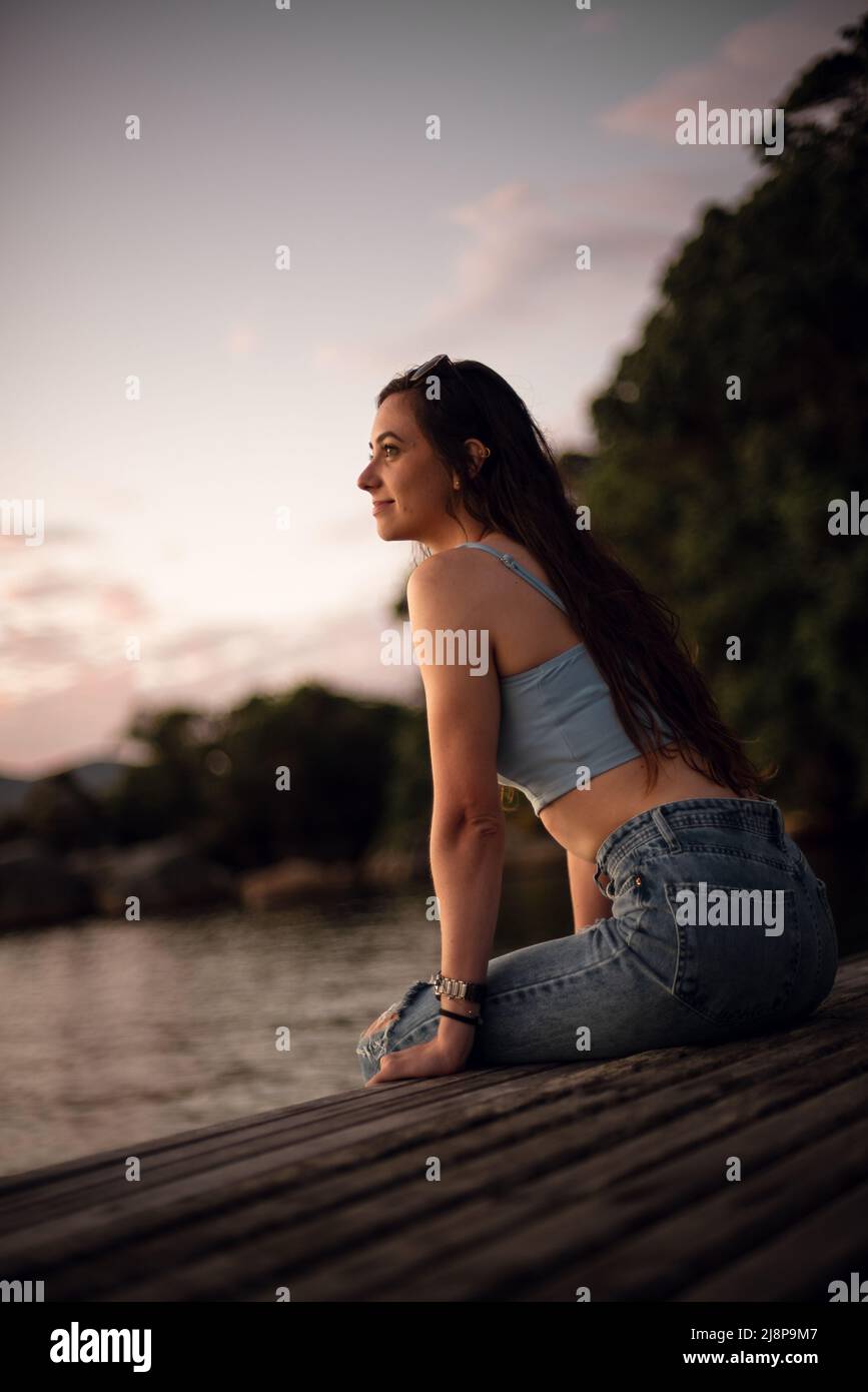 young woman sit in front of a lake and looking at the horizon Stock Photo